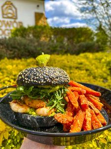 Burger z czarną bułką i krewetkami w ogródku resturacyjnym Dworu Bogucin